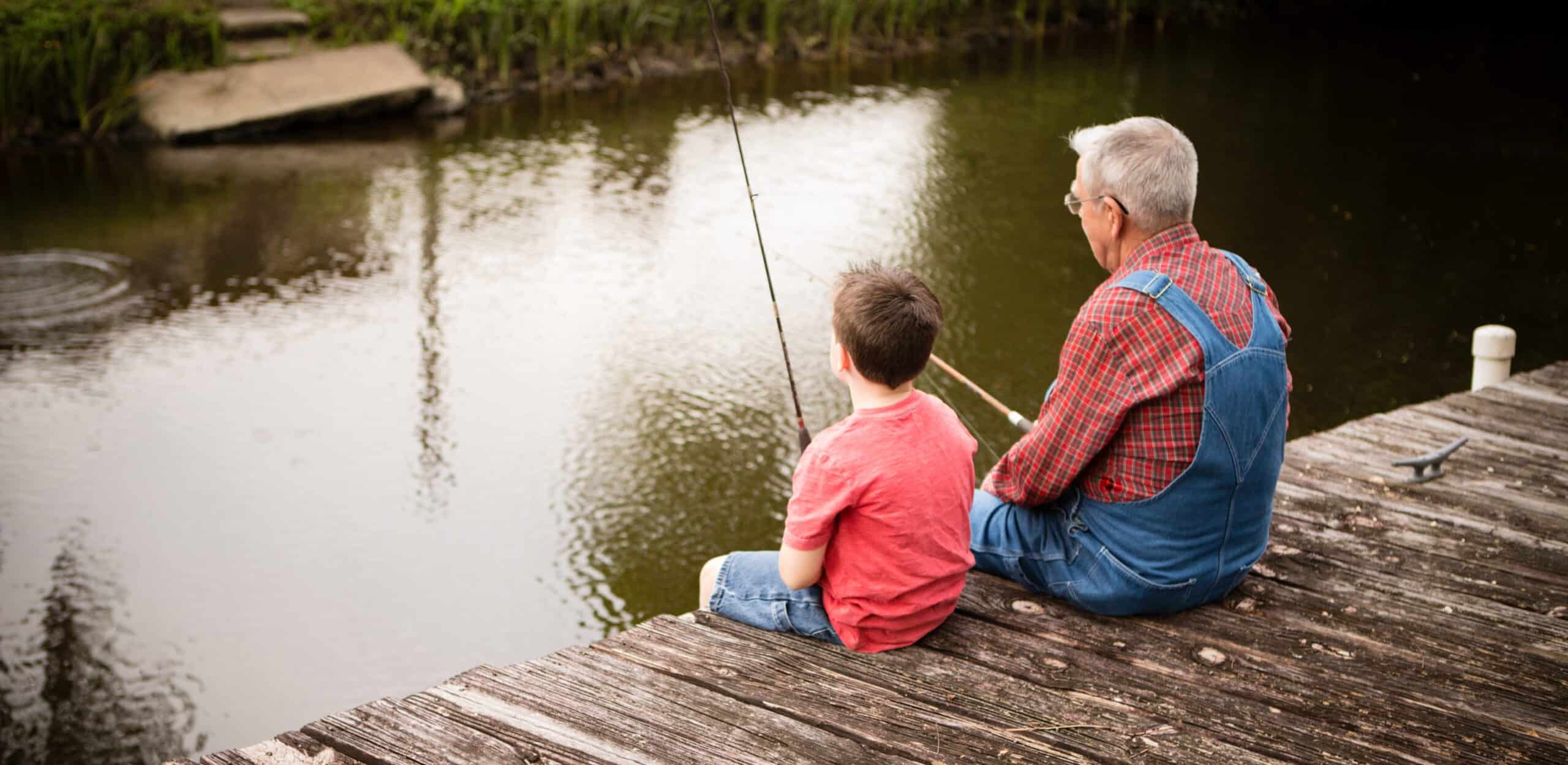 Grandfather and grandfather fishing off of a dock sharing family stories