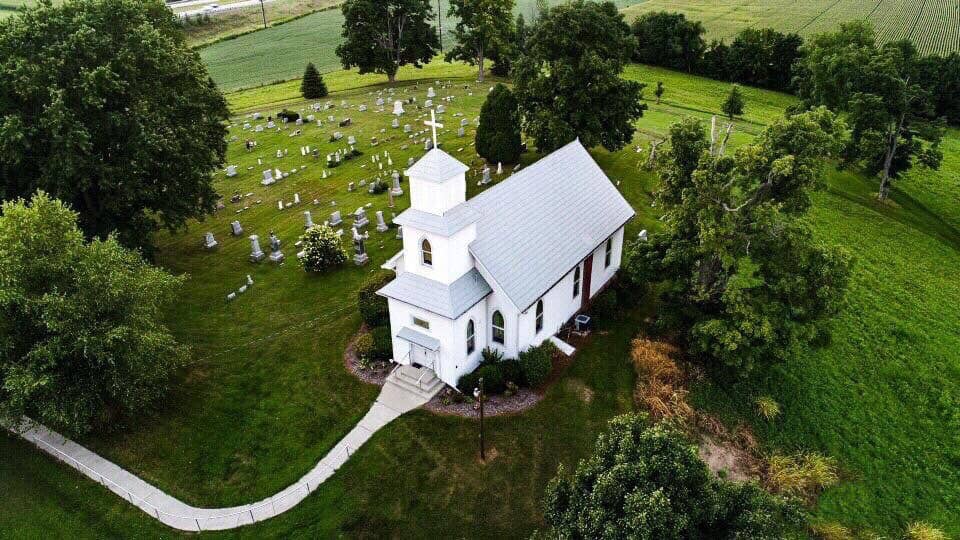 drone shot of a white church in Ohio surrounded by a cemetery